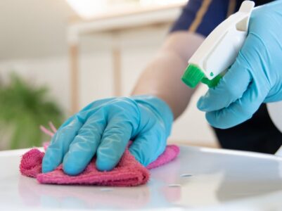 Home cleaning team using disinfectant spray in a kitchen.